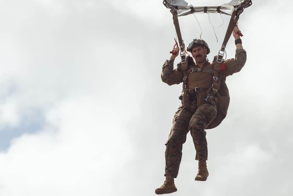Marine parachutist descends toward the water during aerial insertion training